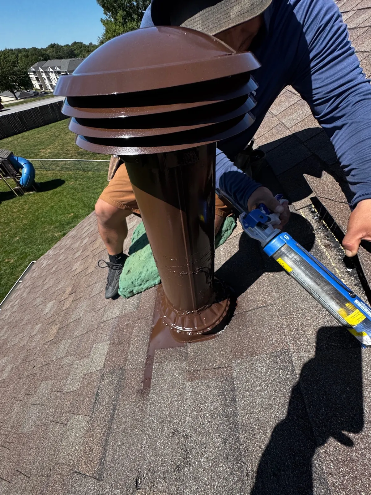 Highland Remodeling crew member sealing the flashing around a repainted vent stack